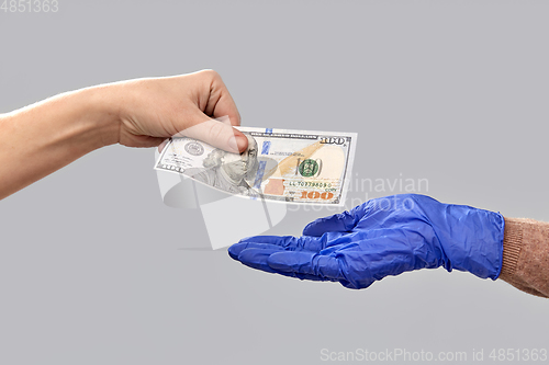 Image of close up of hand in medical glove giving money