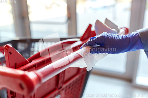 Image of hand cleaning shopping cart handle with wet wipe