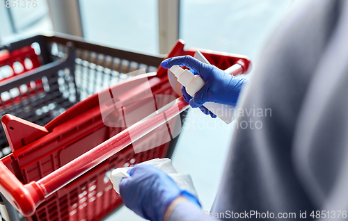 Image of woman cleaning shopping cart handle with sanitizer