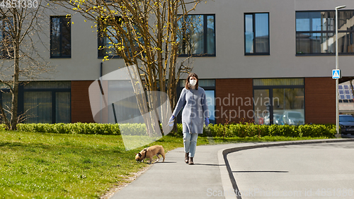 Image of woman in mask and gloves with dog walking in city