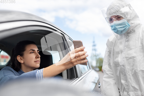 Image of woman in car showing phohe to healthcare worker