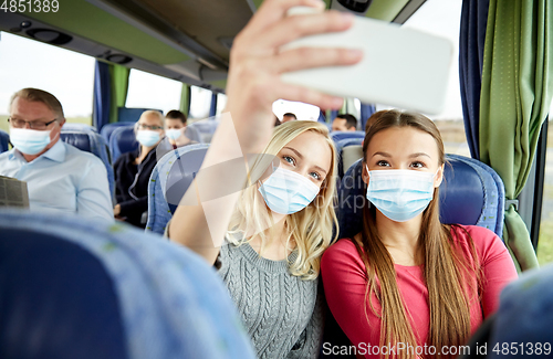 Image of women in medical masks taking selfie in travel bus