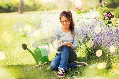 Image of young woman writing to notebook at summer garden