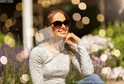 Image of happy young woman in sunglasses at summer garden