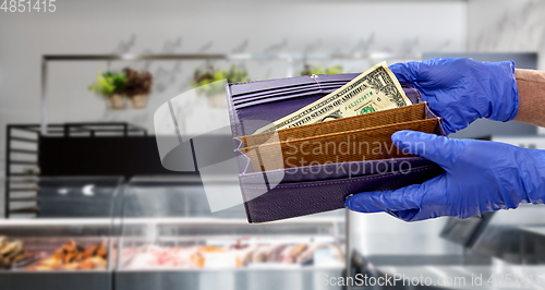 Image of close up of hands in gloves with dollar in wallet