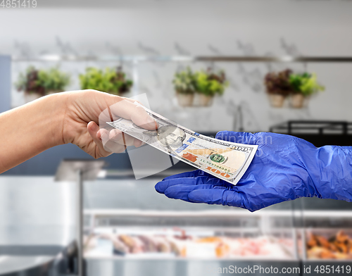 Image of close up of hand in medical glove giving money