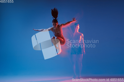 Image of Caucasian professional female athlete training on blue studio background in neon, mixed light. Muscular, sportive woman.