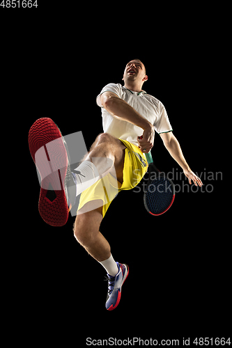 Image of Young caucasian tennis player in action, motion isolated on black background, look from the bottom. Concept of sport, movement, energy and dynamic.