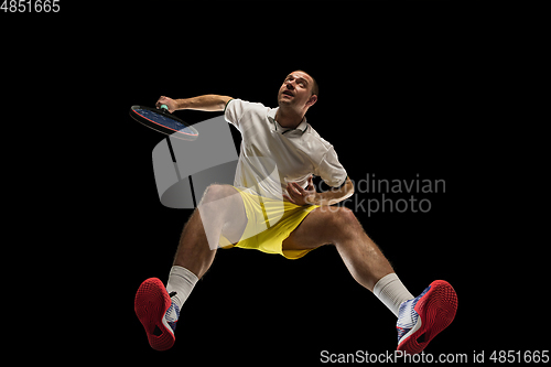 Image of Young caucasian tennis player in action, motion isolated on black background, look from the bottom. Concept of sport, movement, energy and dynamic.