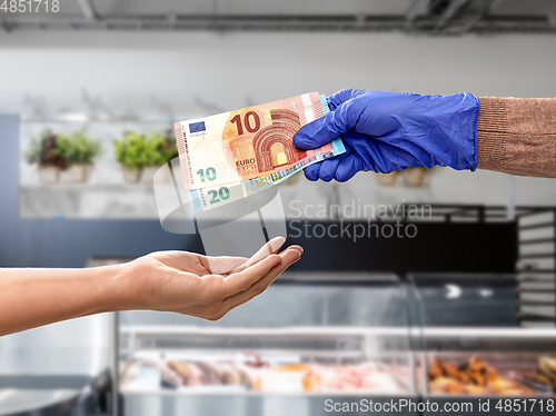 Image of close up of hand in medical glove paying money