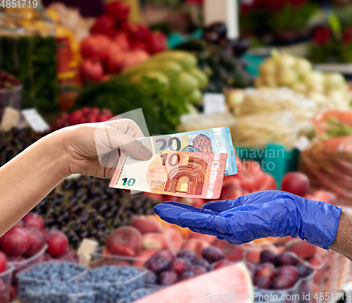 Image of close up of hand in medical glove giving money