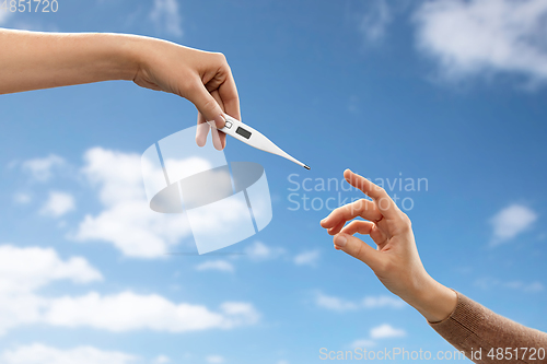 Image of close up of hands giving each other thermometer