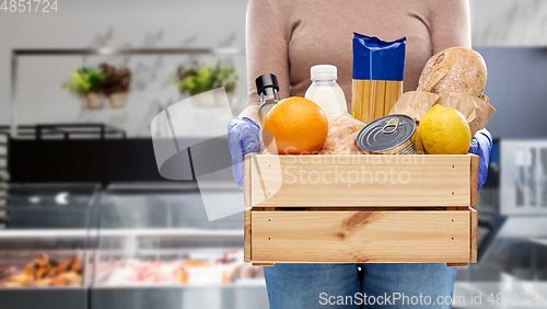 Image of woman in gloves with food in wooden box