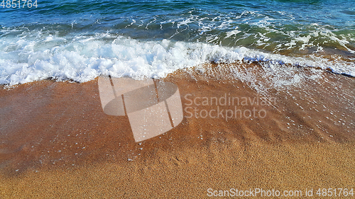 Image of Sea wave with white foam on the coastal sand