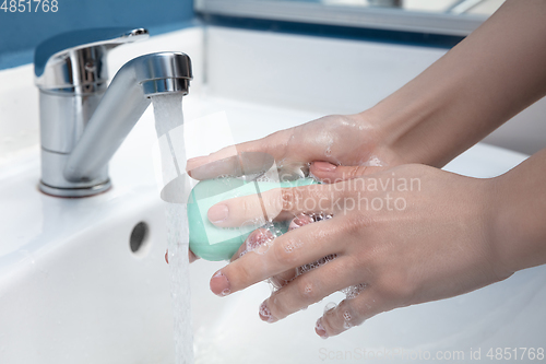 Image of Woman washing hands carefully in bathroom close up. Prevention of infection and pneumonia virus spreading