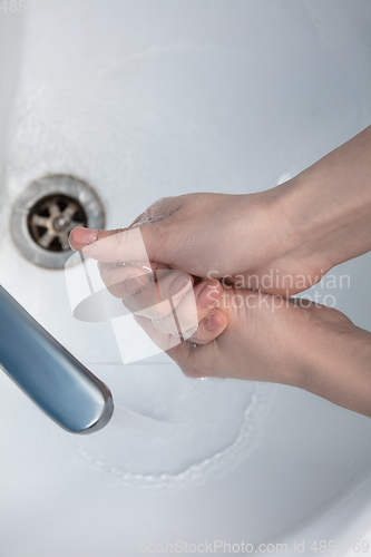 Image of Woman washing hands carefully in bathroom close up. Prevention of infection and pneumonia virus spreading