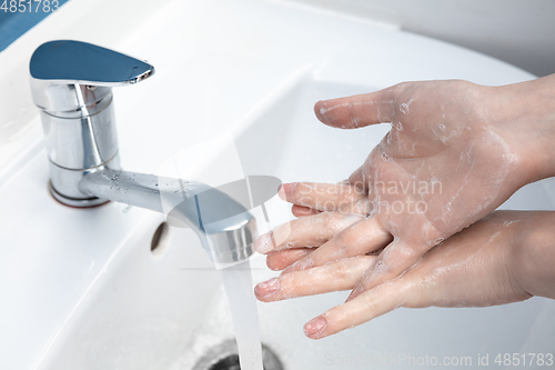 Image of Woman washing hands carefully in bathroom close up. Prevention of infection and pneumonia virus spreading