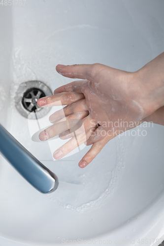 Image of Woman washing hands carefully in bathroom close up. Prevention of infection and pneumonia virus spreading