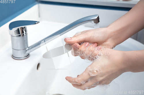 Image of Woman washing hands carefully in bathroom close up. Prevention of infection and pneumonia virus spreading