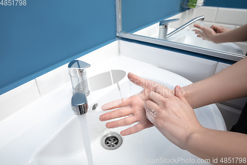 Image of Woman washing hands carefully in bathroom close up. Prevention of infection and pneumonia virus spreading