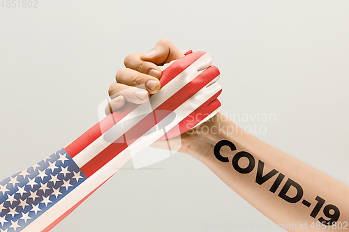 Image of Human hands colored in flag of United States of America and coronavirus - concept of spreading of virus, fighting.