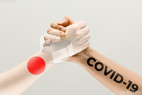 Image of Human hands colored in flag of Japan and coronavirus - concept of spreading of virus, fighting