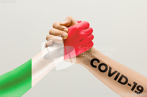 Image of Human hands colored in flag of Italy and coronavirus - concept of spreading of virus, fighting