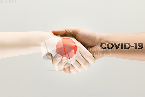 Image of Human hands colored in flag of Japan and coronavirus - concept of spreading of virus