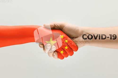 Image of Human hands colored in flag of China and coronavirus - concept of spreading of virus