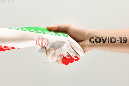 Image of Human hands colored in flag of Iran and coronavirus - concept of spreading of virus