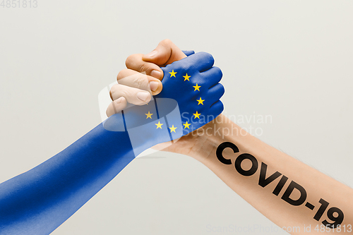 Image of Human hands colored in flag of Europian Union and coronavirus - concept of spreading of virus, fighting