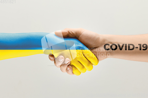 Image of Human hands colored in flag of Ukraine and coronavirus - concept of spreading of virus