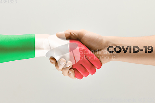 Image of Human hands colored in flag of Italy and coronavirus - concept of spreading of virus