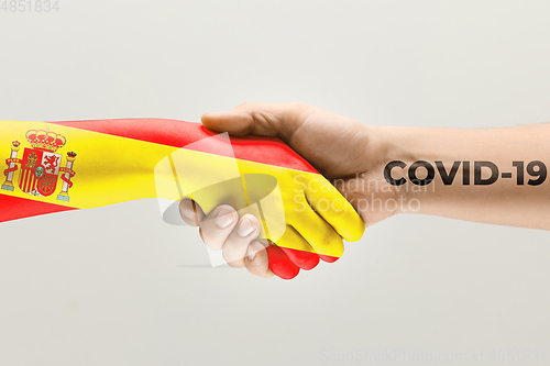 Image of Human hands colored in flag of Spain and coronavirus - concept of spreading of virus, fighting