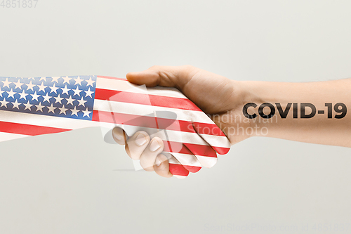 Image of Human hands colored in flag of United States of America and coronavirus - concept of spreading of virus