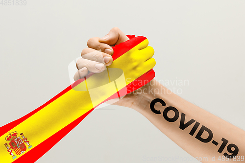 Image of Human hands colored in flag of Spain and coronavirus - concept of spreading of virus, fighting