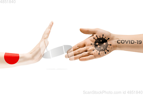 Image of Stop shaking hands. Human hands colored in flag of Japan and coronavirus - concept of spreading of virus