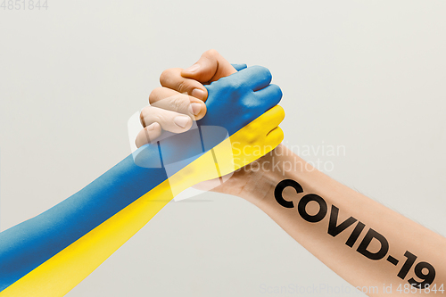 Image of Human hands colored in flag of Ukraine and coronavirus - concept of spreading of virus, fighting