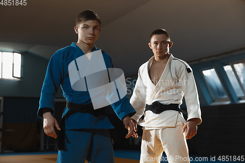 Image of Two young judo fighters in kimono posing comfident in the gym, strong and healthy