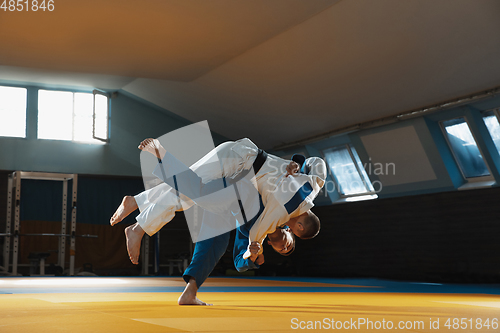 Image of Two young judo fighters in kimono training martial arts in the gym with expression, in action and motion