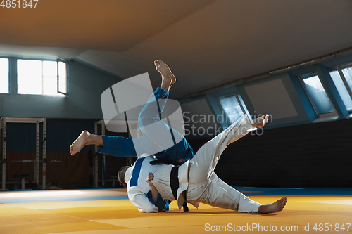 Image of Two young judo fighters in kimono training martial arts in the gym with expression, in action and motion