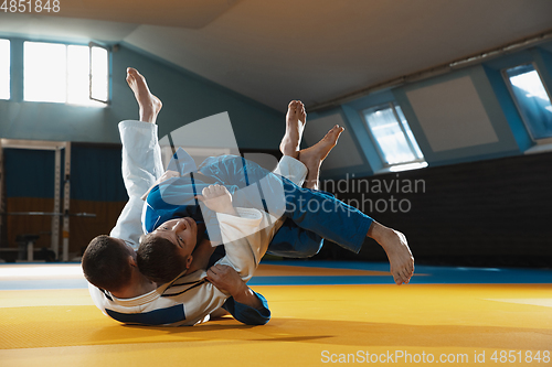 Image of Two young judo fighters in kimono training martial arts in the gym with expression, in action and motion