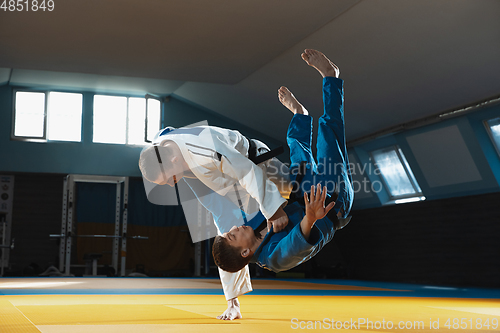 Image of Two young judo fighters in kimono training martial arts in the gym with expression, in action and motion