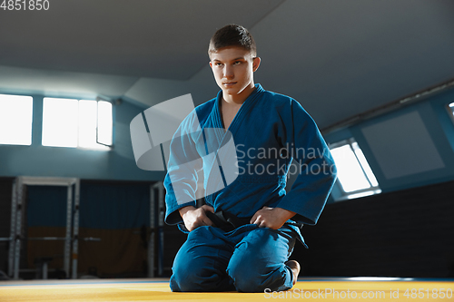 Image of Young judo fighter in kimono posing comfident in the gym, strong and healthy