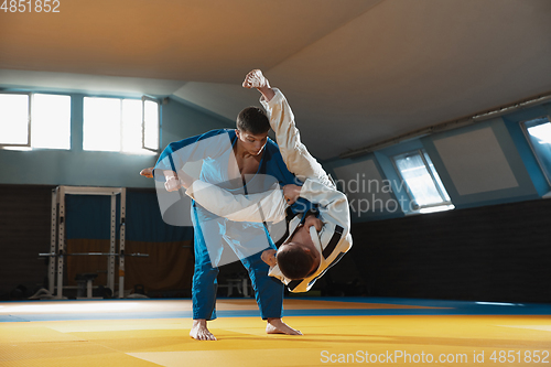 Image of Two young judo fighters in kimono training martial arts in the gym with expression, in action and motion