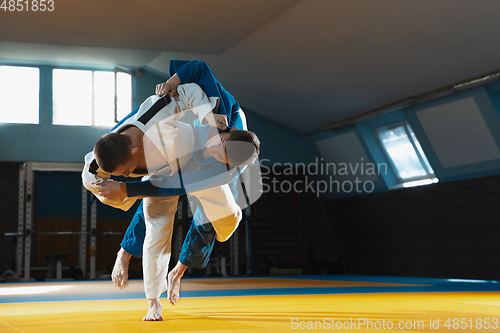 Image of Two young judo fighters in kimono training martial arts in the gym with expression, in action and motion