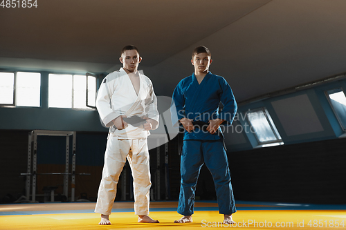 Image of Two young judo fighters in kimono posing comfident in the gym, strong and healthy