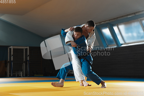 Image of Two young judo fighters in kimono training martial arts in the gym with expression, in action and motion