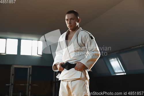 Image of Young judo fighter in kimono posing comfident in the gym, strong and healthy