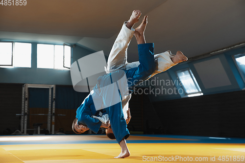 Image of Two young judo fighters in kimono training martial arts in the gym with expression, in action and motion